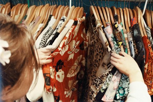 femme qui regarde des vêtements sur des cintres dans un magasin